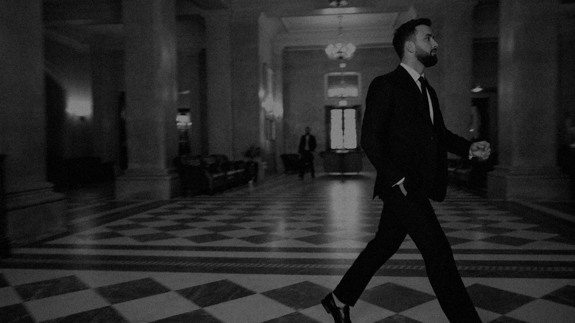 Noah Merriby in a suit in a grand lobby, black and white
